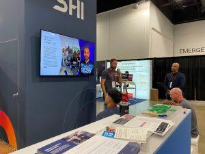 Reece Hartle, Senior Education Strategist, addresses an audience at the SHI booth on the conference floor.