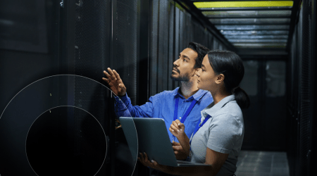 Two IT technicians examine a server room